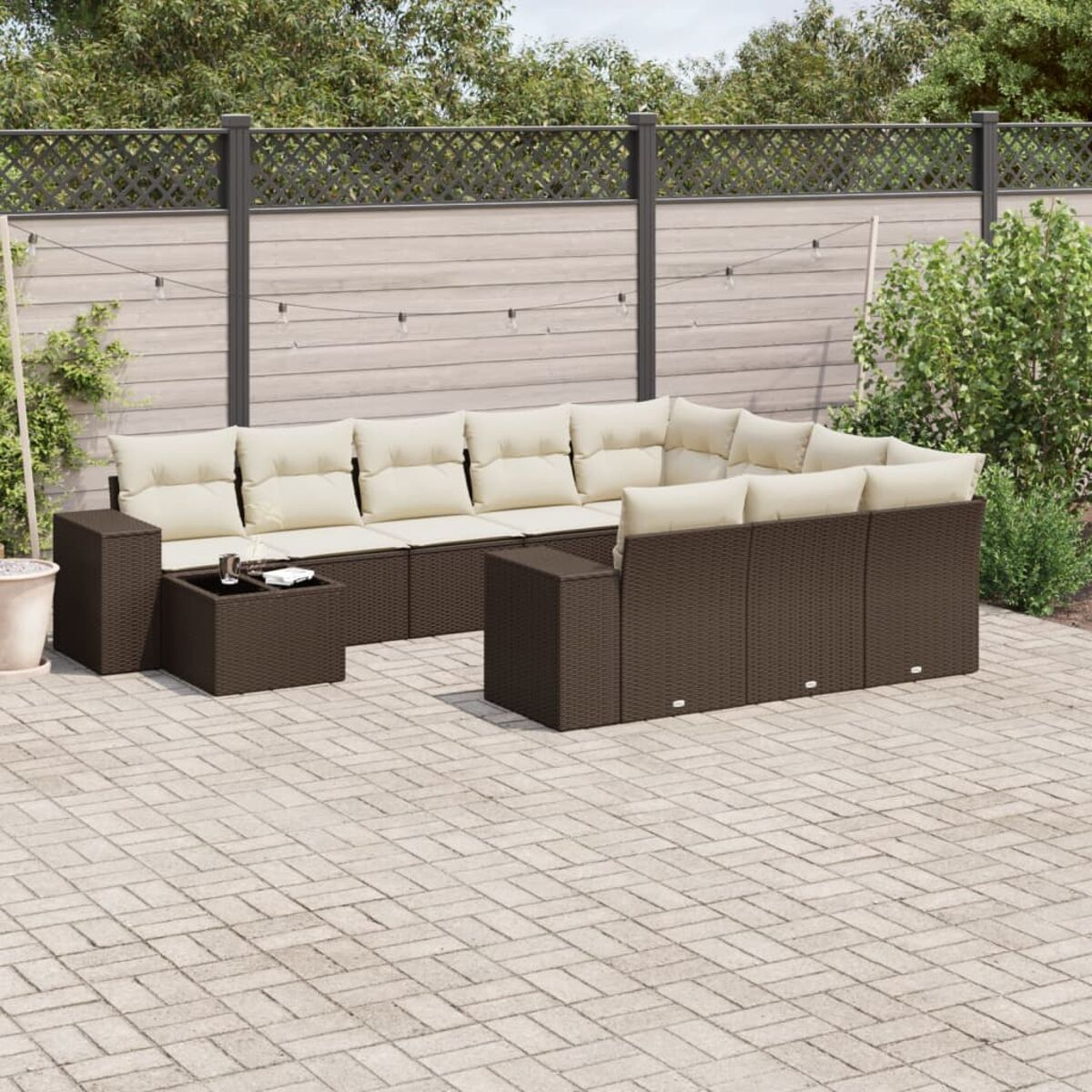 Set patio esterno marrone scuro con cuscini beige e tavolino. Patio in mattoni al sole.