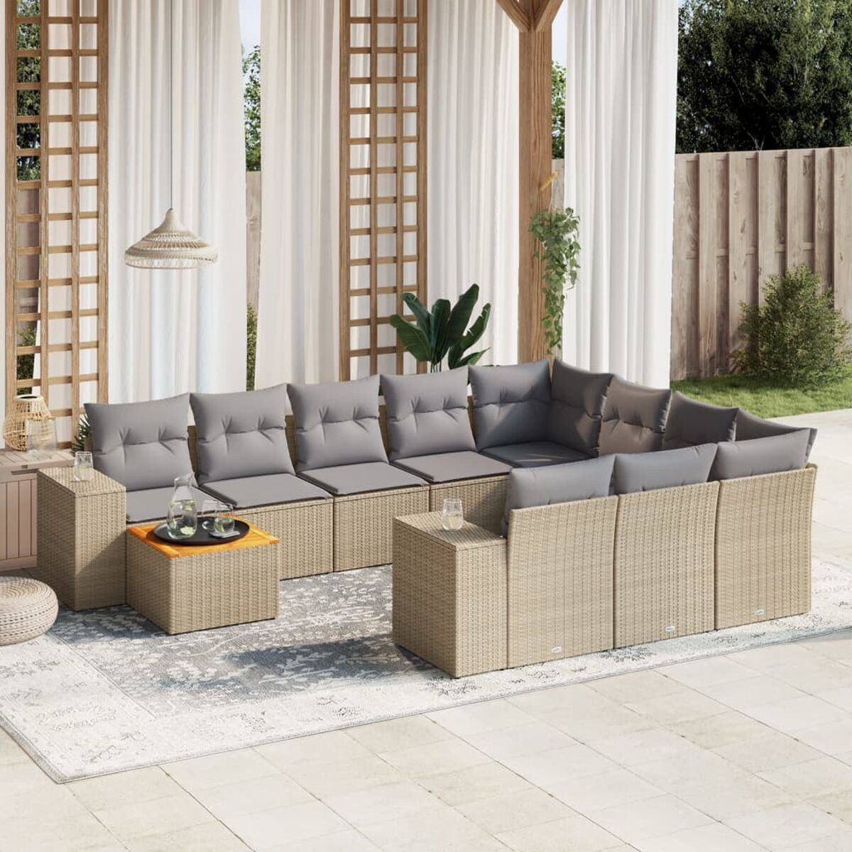 Outdoor-Sitzgruppe mit beigem Korbsessel, Stühlen und Tisch. Graue Kissen und gemusterter Teppich.