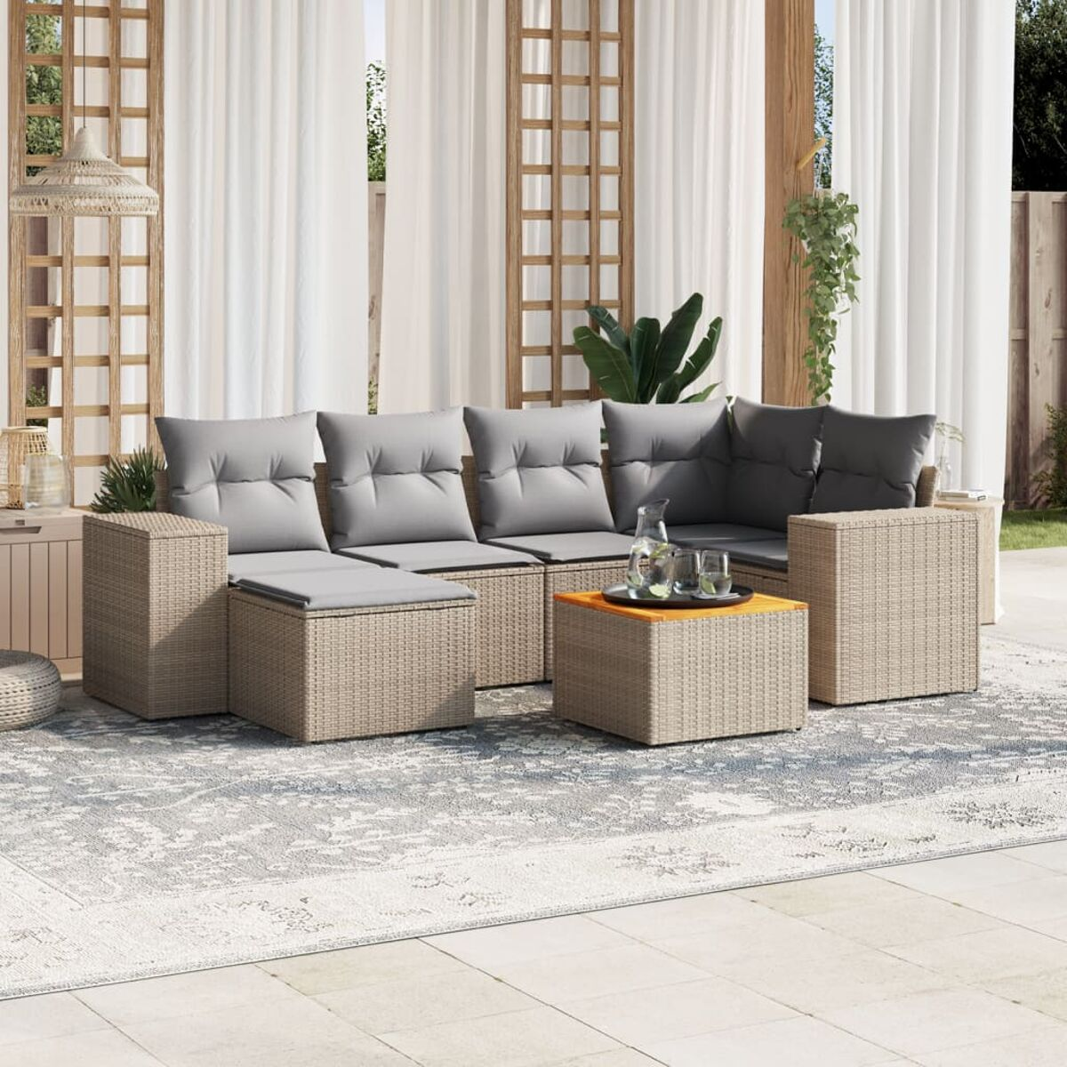 Wicker-Lounge mit grauen Kissen und einem kleinen Tisch auf einem Teppich auf einer Terrasse.