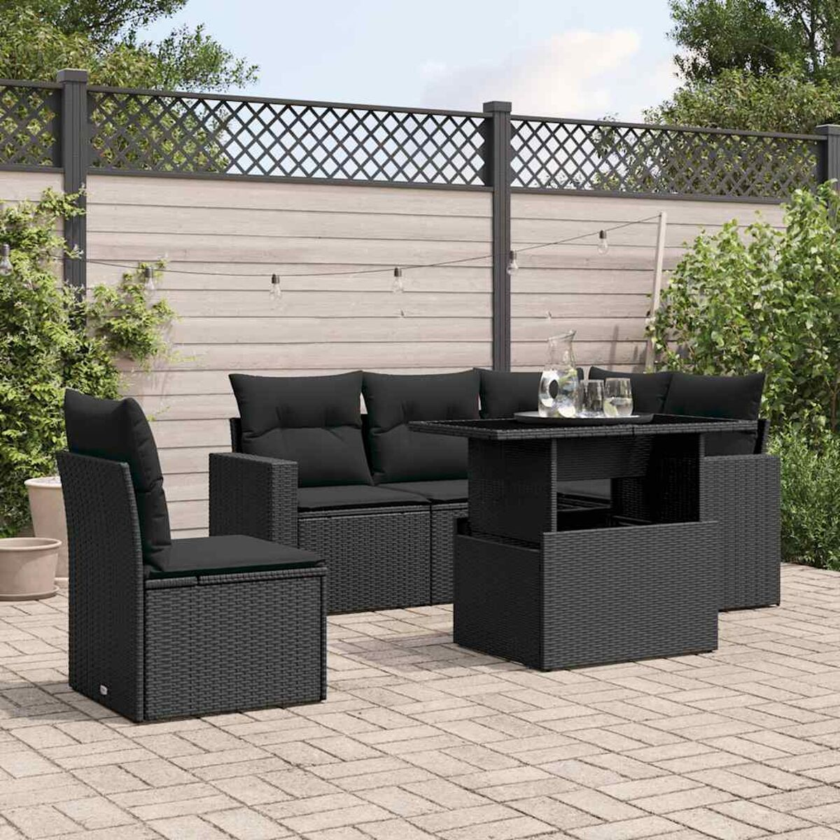 Schwarzes Rattan-Sofa mit einem Tisch mit Hubplatte und einem Stuhl auf einer Terrasse.