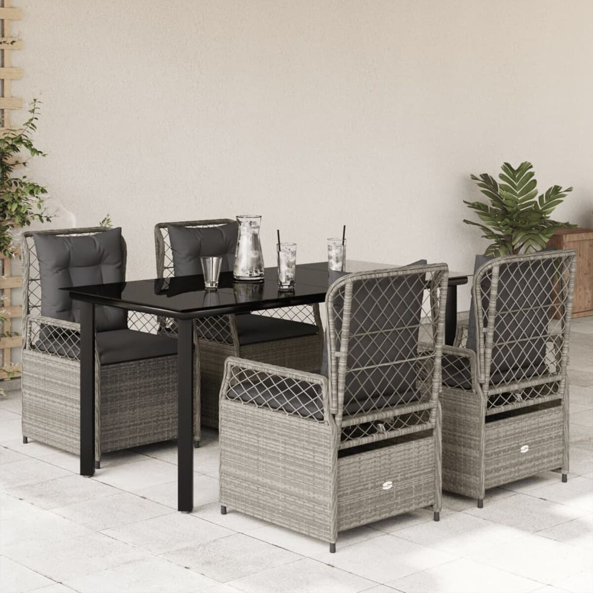 Ein Terrassenset mit einem schwarzen Tisch, vier Stühlen mit grauen Kissen, vor einer beigen Wand.
