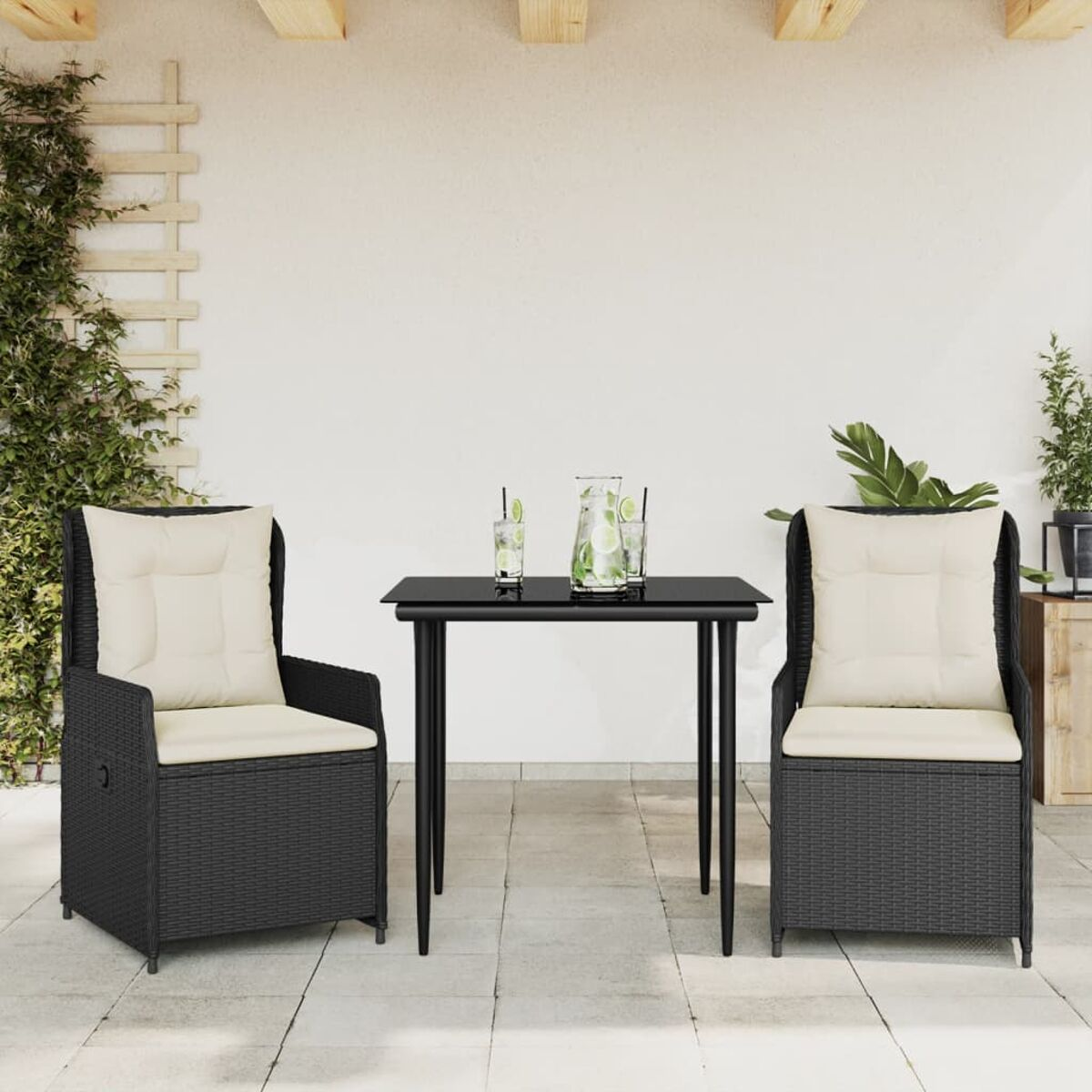 Set da pranzo all'aperto con due sedie e un tavolo. Sedie in vimini nero con cuscini color crema. Tavolo nero.