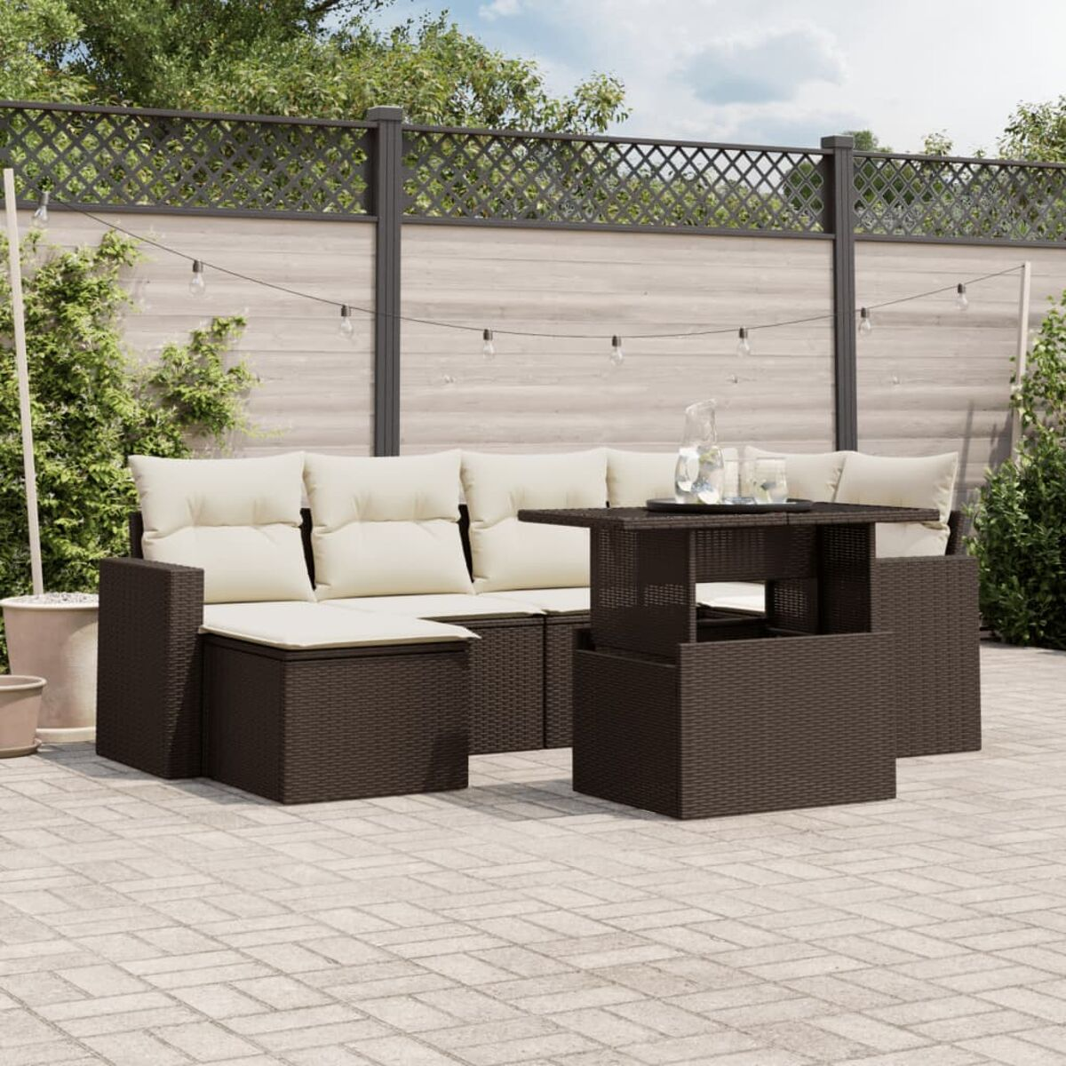 Dunkelbraunes Terrassenset mit Sofa, Tisch und Ottomane auf einer gepflasterten Terrasse. Weiße Kissen.