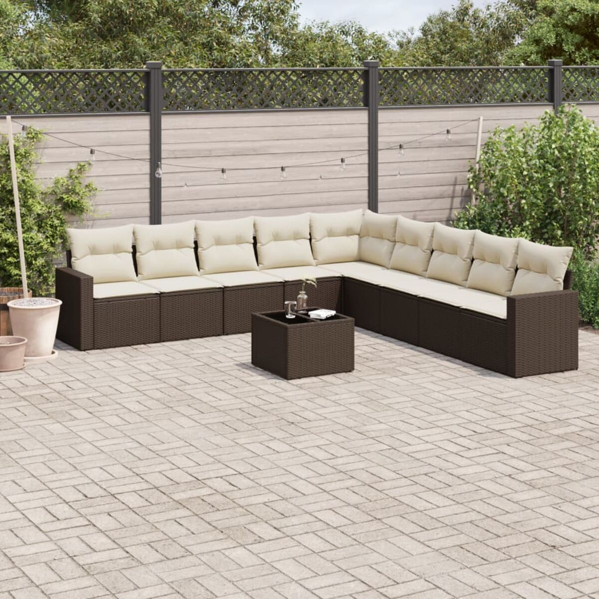 Un set di divani in vimini marrone e un tavolo su un patio pavimentato. Cuscini beige.