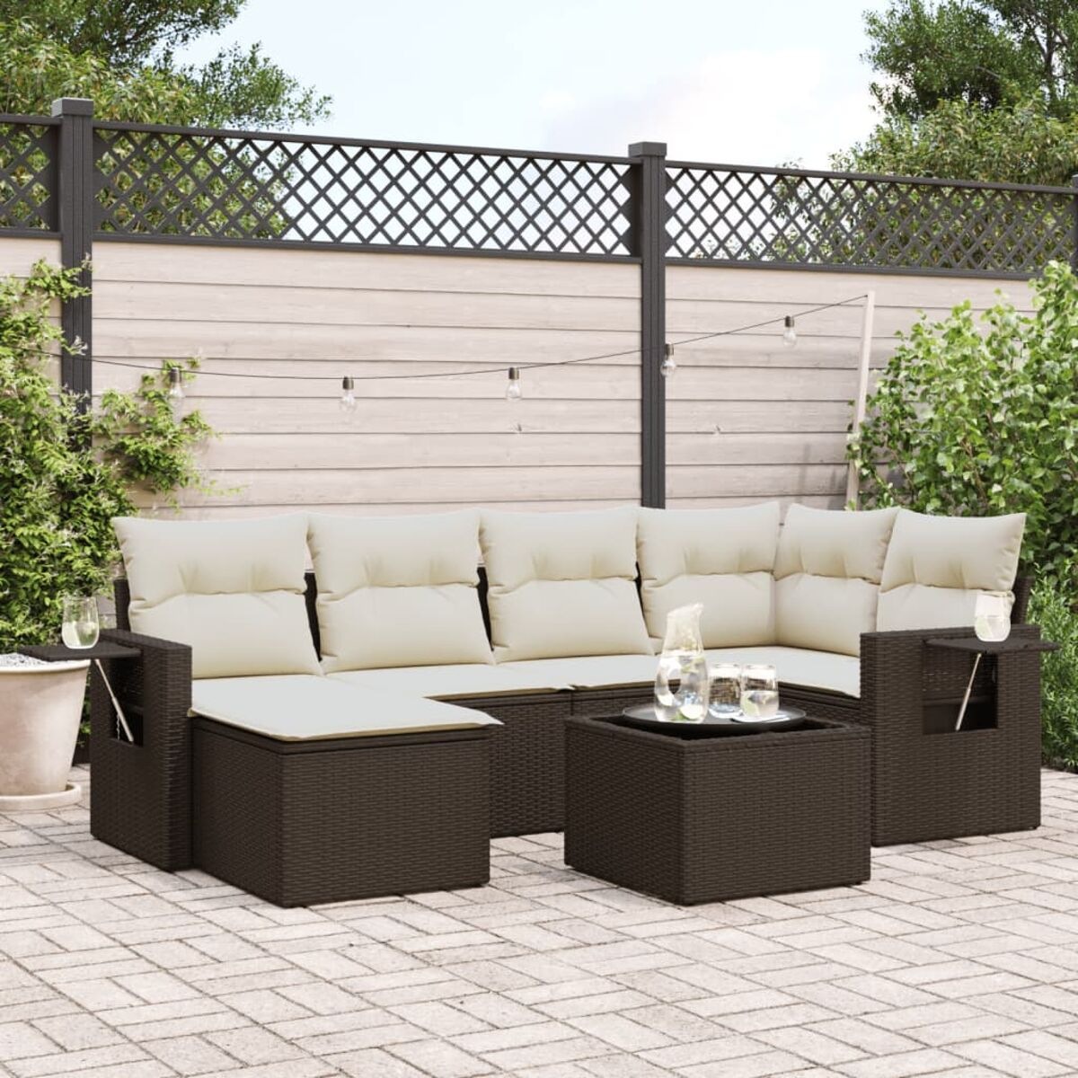 Divano componibile in vimini marrone con cuscini color crema, tavolo e ambiente.