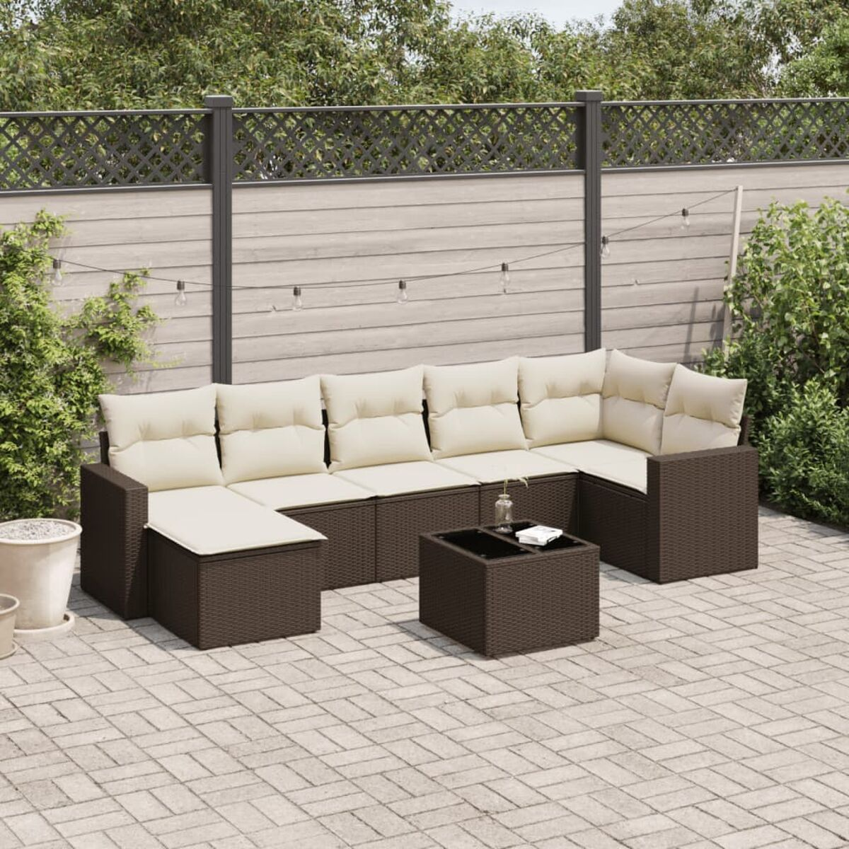 Divano componibile marrone da esterno con cuscini color crema, tavolo e un patio pavimentato.