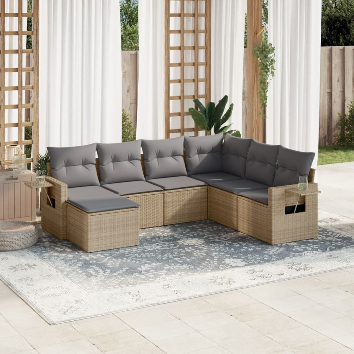 Ecksofa aus Korbgeflecht mit Kissen, einem Teppich und Beistelltischen auf einer Terrasse.