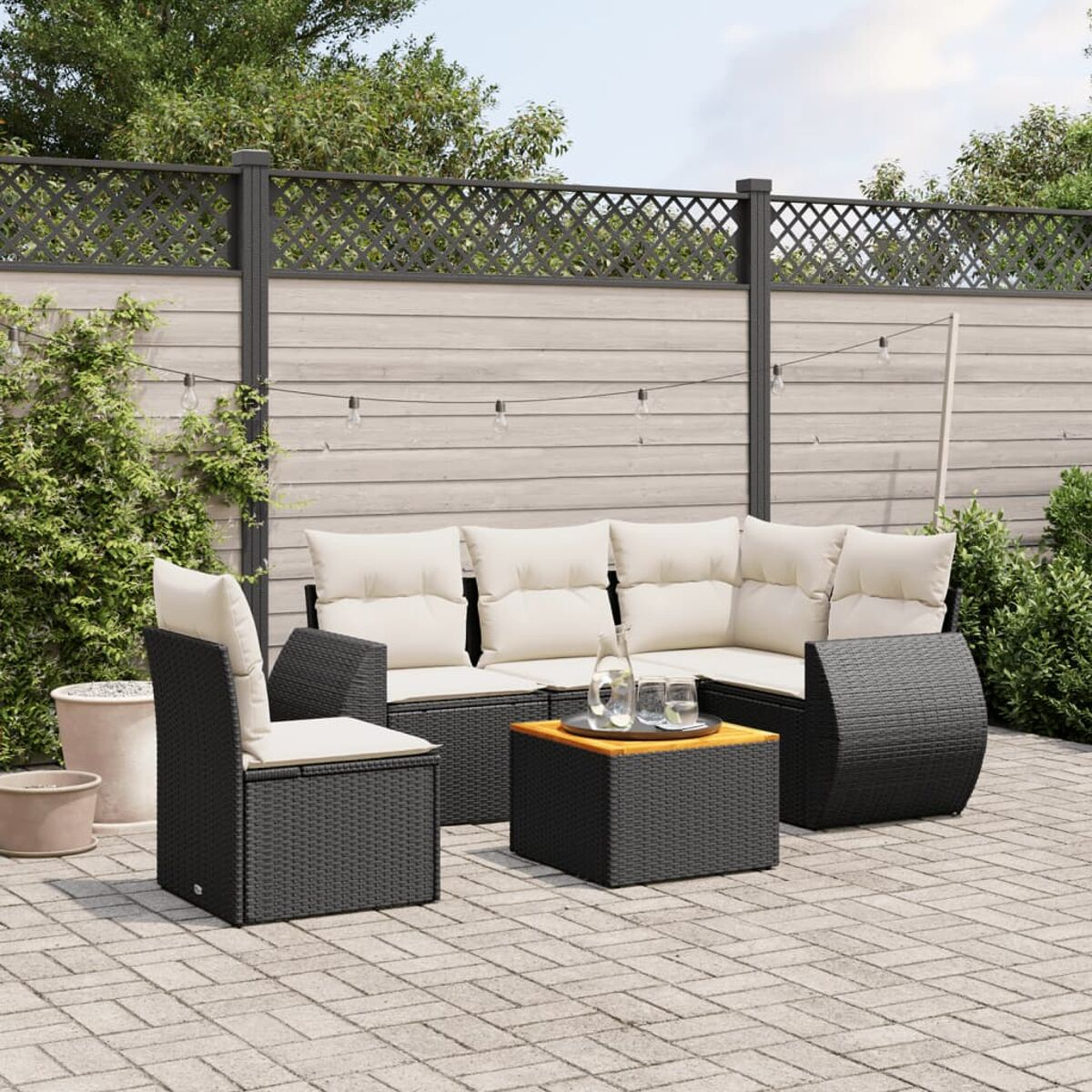 Outdoor-Sitzbereich mit schwarzen Rattanmöbeln, beigen Kissen und Holztisch.