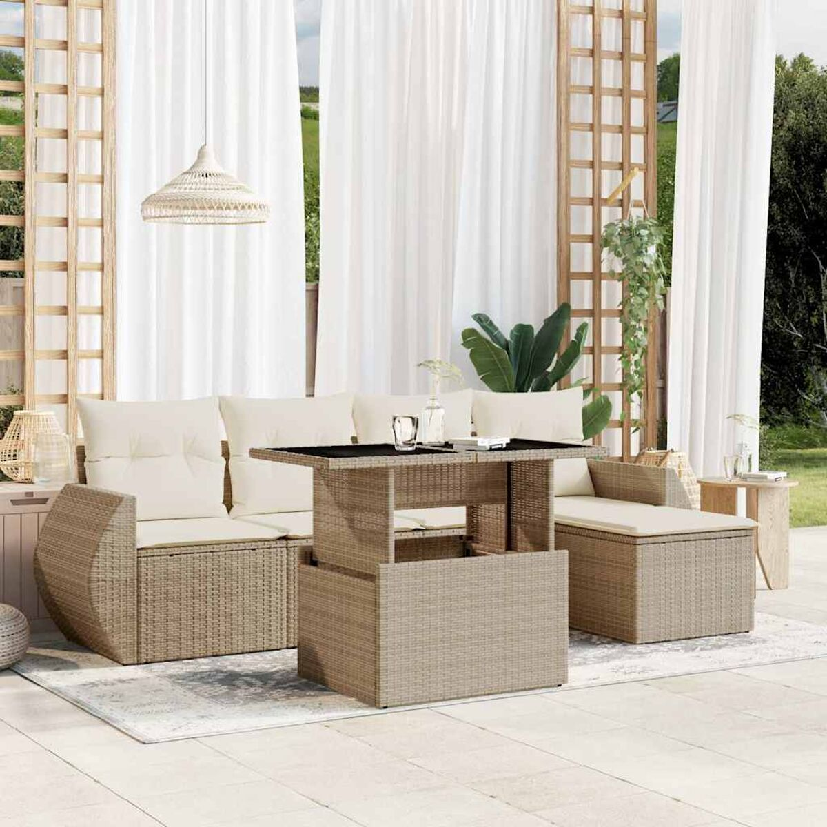 Gartenmöbel-Set aus Rattan mit Tisch und Kissen. Weiße Vorhänge, ein Teppich und Pflanzen.
