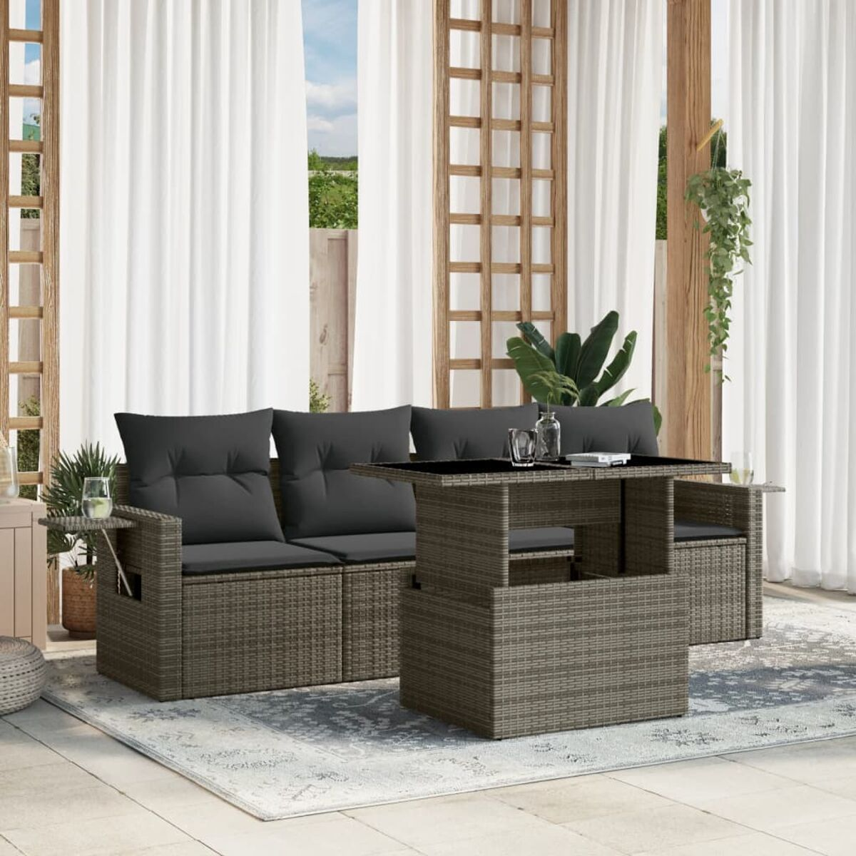 Outdoor-Sitzgruppe mit einem Tisch mit Hubfunktion auf einem gemusterten Teppich, im Garten. Vorhänge im Hintergrund.