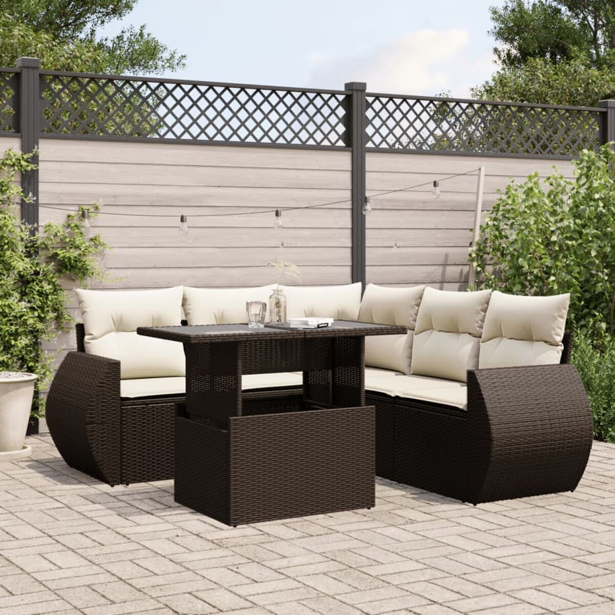 Outdoor-Sitzgruppe mit einem Tisch mit Hubfunktion auf einer Backsteinterrasse. Das Set ist dunkelbraun mit cremefarbenen Kissen.