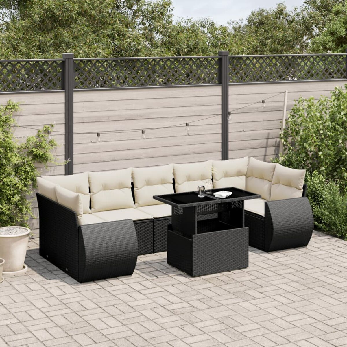 Schwarzes Outdoor-Ecksofa mit cremefarbenen Kissen, Couchtisch und Teppich.
