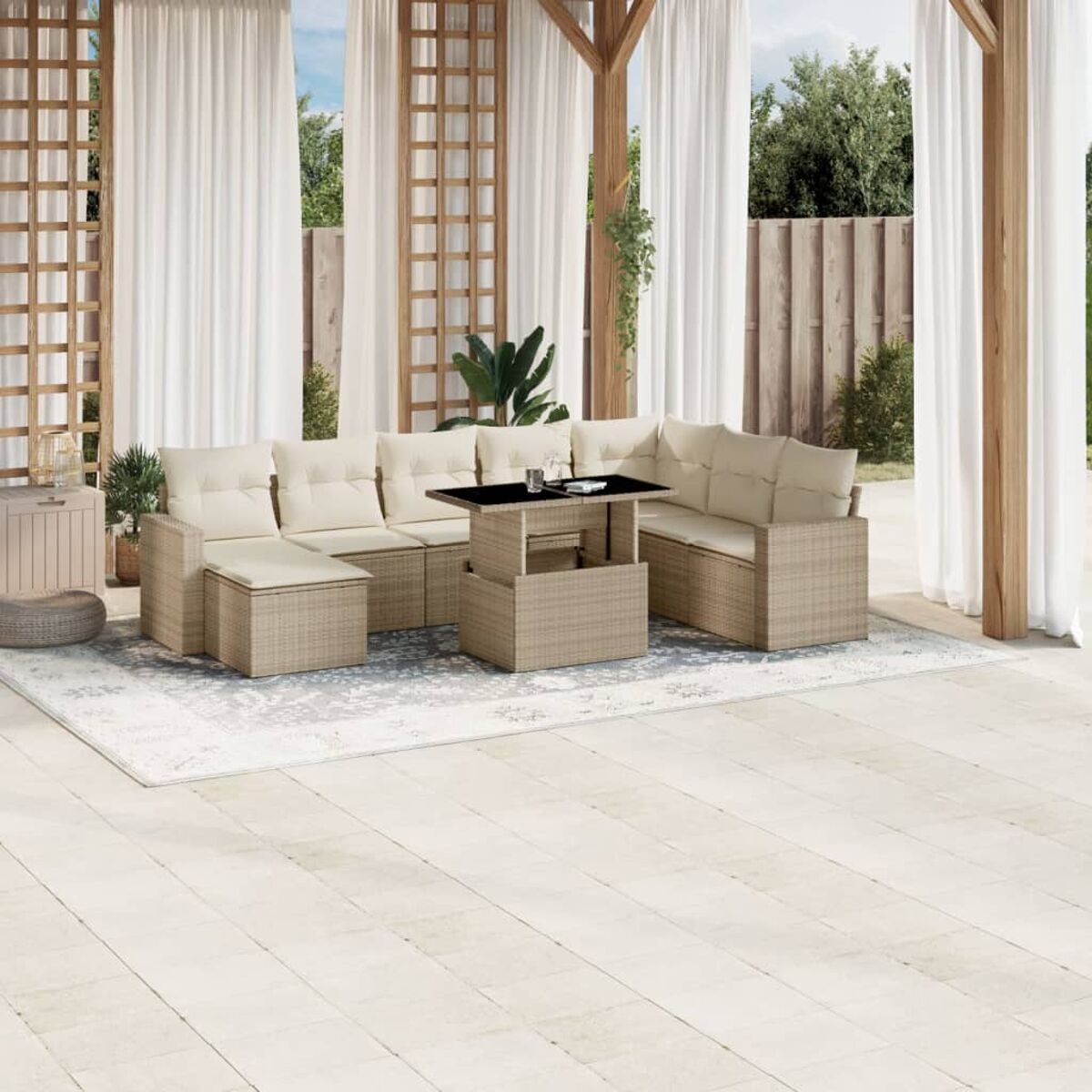 Terrassenmöbel-Set auf einer Terrasse mit Teppich und Vorhängen. Beiges Rattan-Sofa und ein Tisch mit Platte.