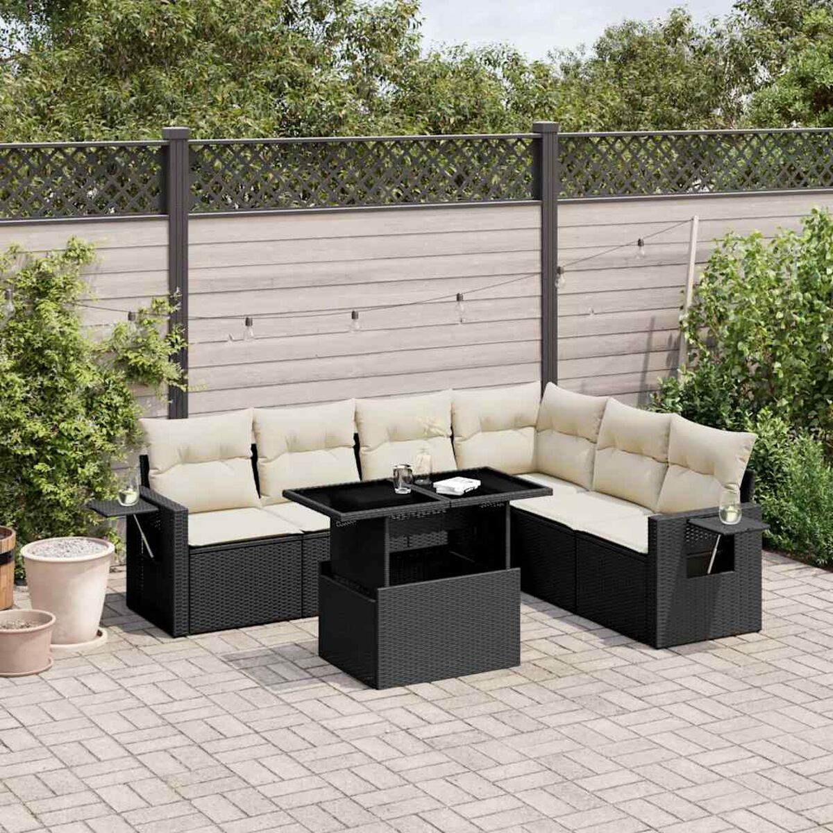 Ein U-förmiges Rattansofa-Set mit cremefarbenen Kissen und einem Couchtisch auf einer gepflasterten Terrasse.