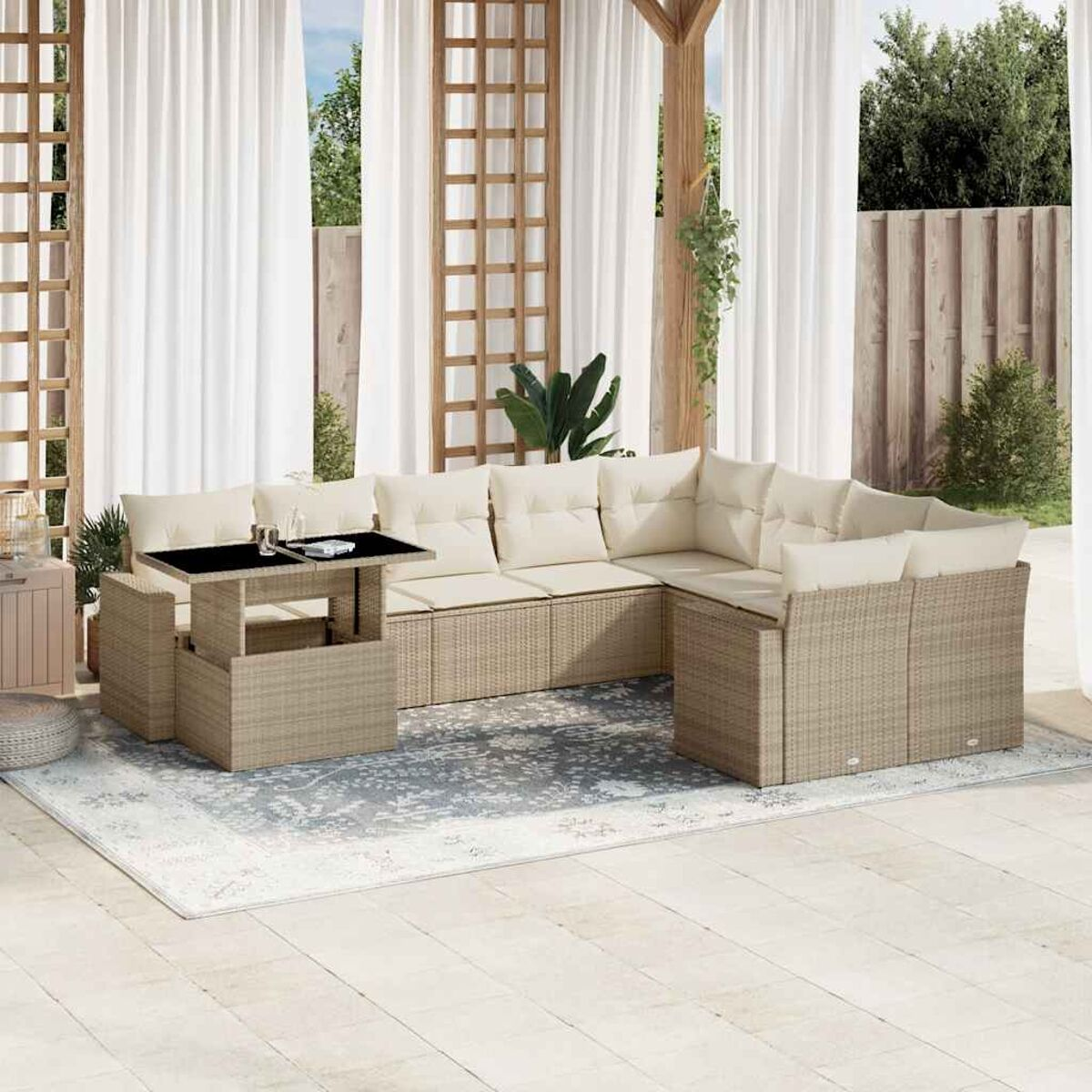 Terrassenmöbel mit beigen Korbsessel, einem Hubtisch und weißen Vorhängen im Hintergrund.