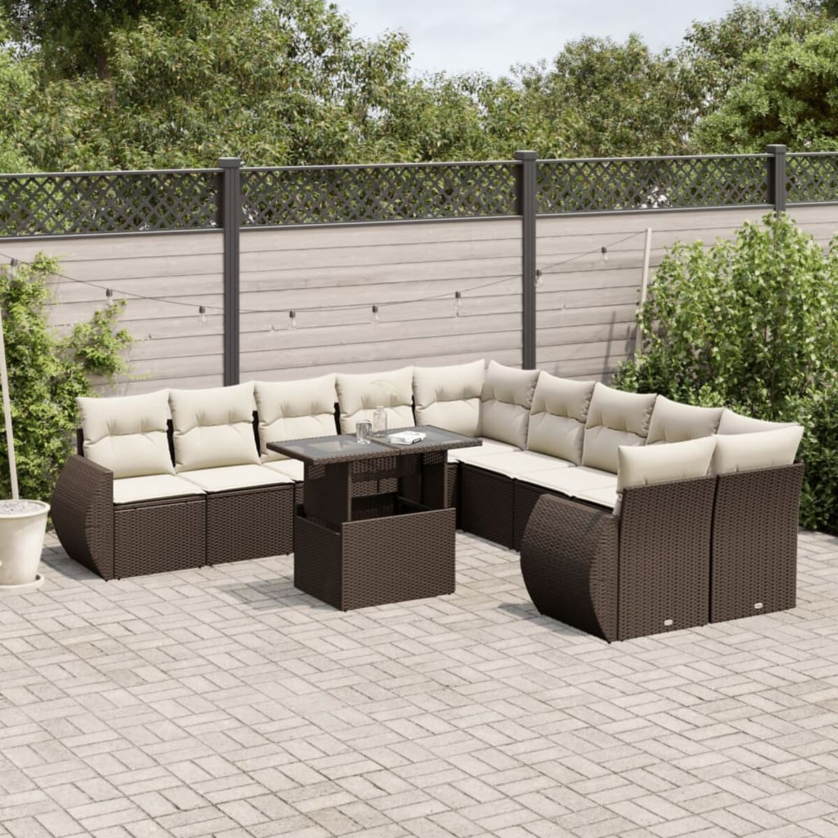 Braunes Ecksofa aus Korbgeflecht mit Couchtisch und beigen Kissen, in einem Garten.