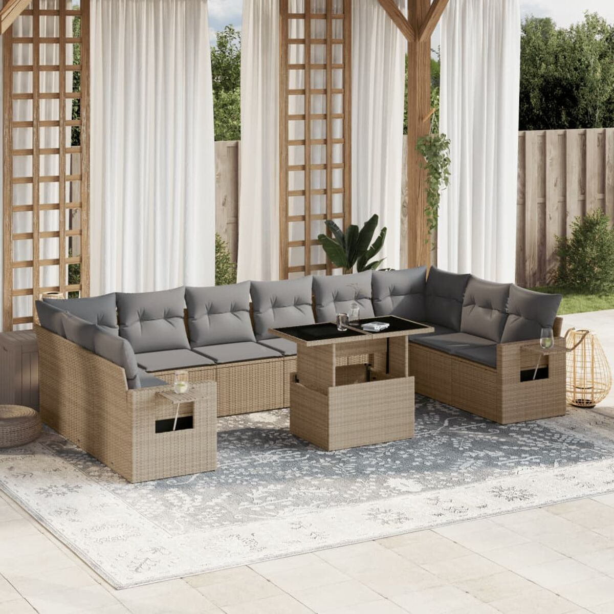 Beige Korbmöbel-Garten-Sitzgruppe mit grauen Kissen, Tisch und Teppich, Vorhänge im Hintergrund.