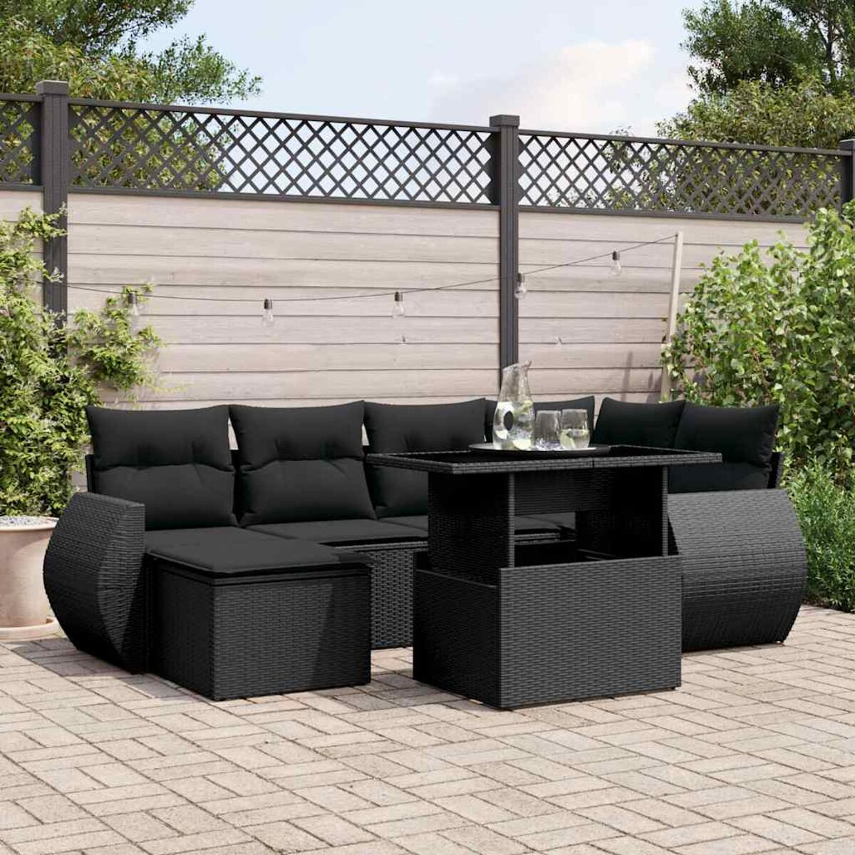 Schwarzes Korbmöbel-Set mit Tisch und Wasserkrug auf der Terrasse.