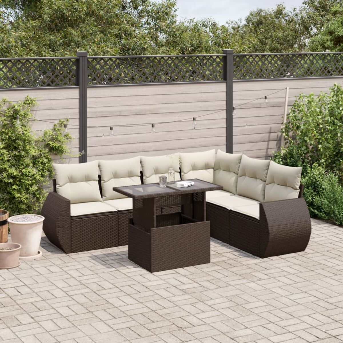 Divano componibile per esterni in rattan marrone con cuscini color crema e tavolo rialzabile.