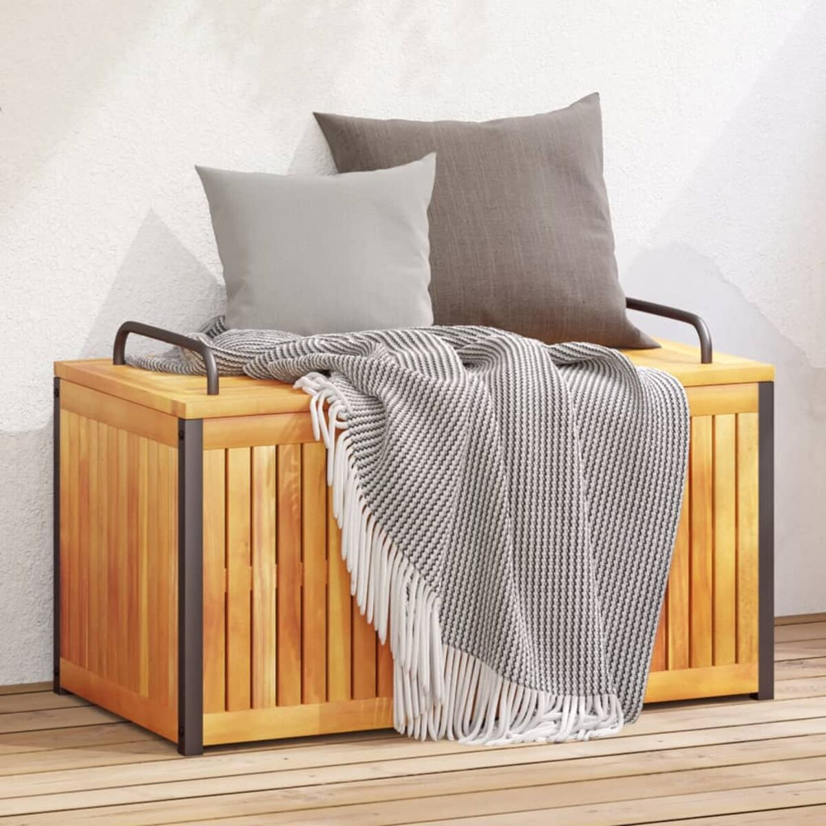 Holzkiste mit Kissen und Decke. Die Kiste hat einen Deckel und Metallgriffe. Umgebung im Freien.