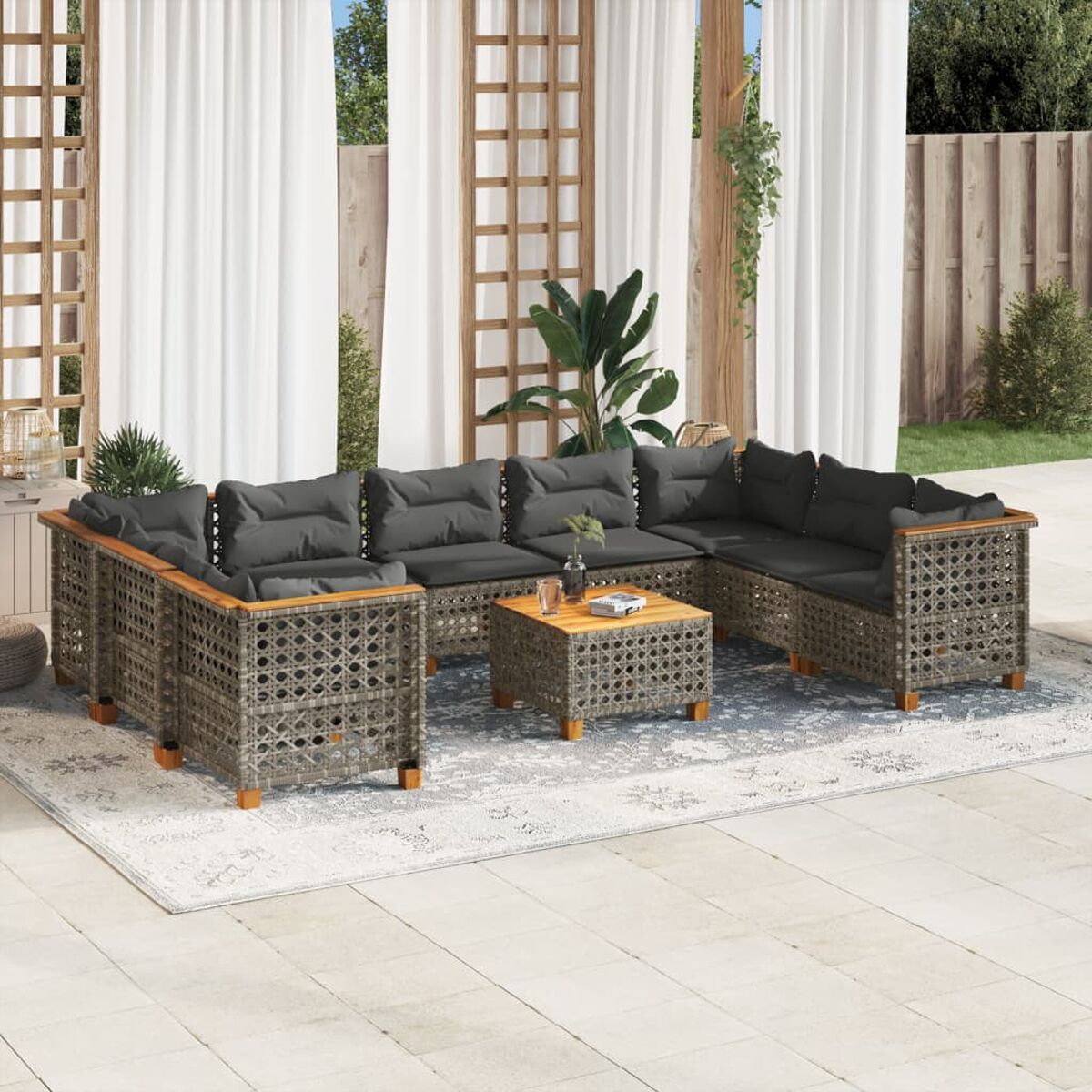 Graues Ecksofa im Freien mit dunklen Kissen und einem Holztisch auf einem gemusterten Teppich.