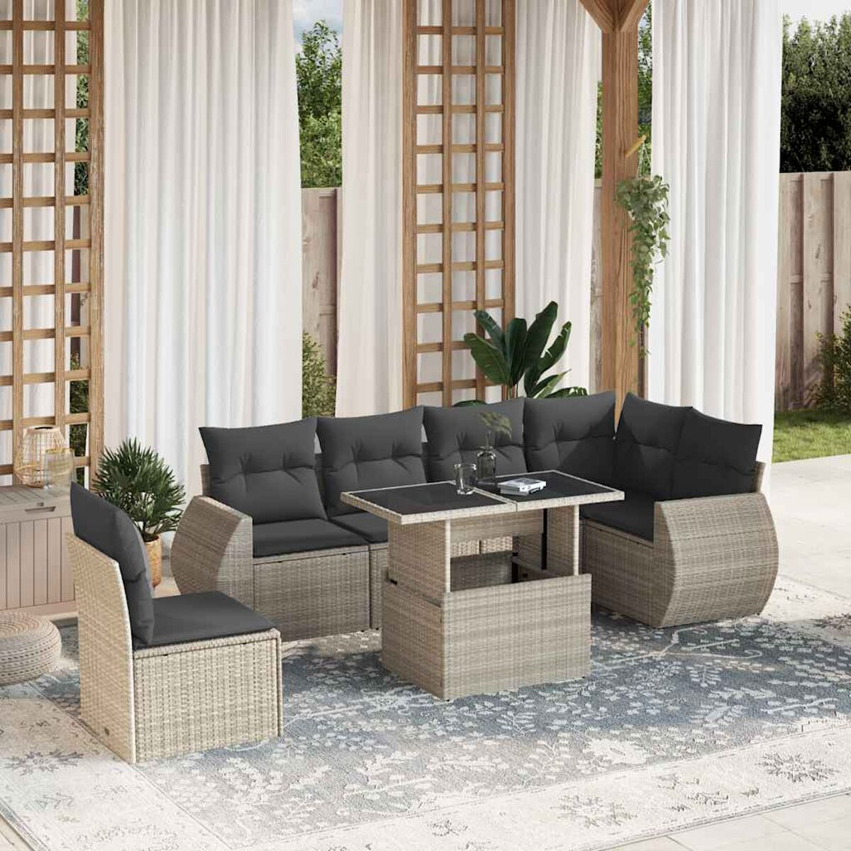Ein Korbmöbel-Set mit Tisch und Stühlen auf einem Teppich. Graue Kissen auf dem Sofa.