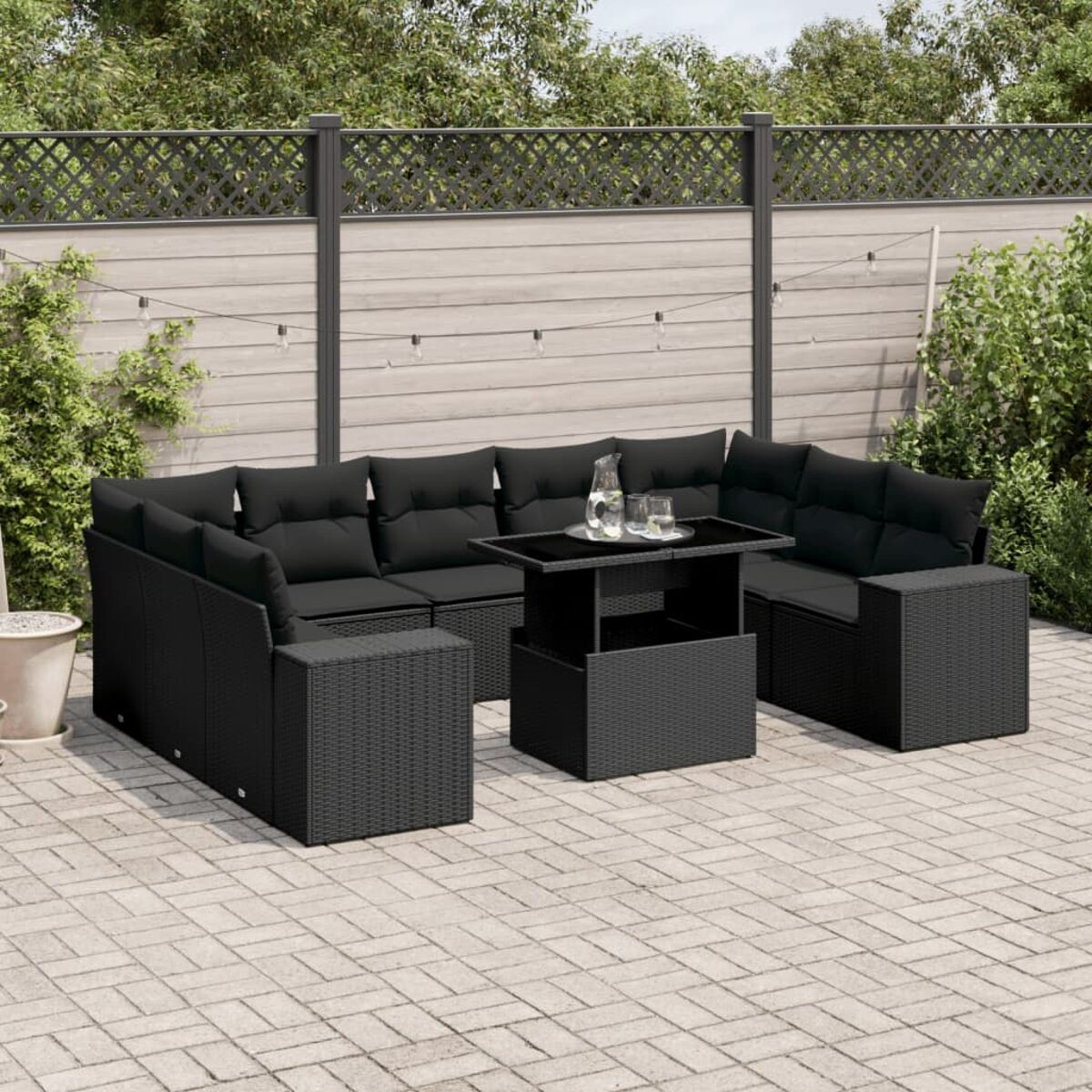 Schwarzes Rattan-Outdoor-Set mit Kissen und Tisch auf einer Terrasse.