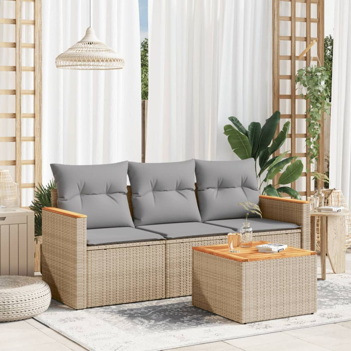 Beiges Rattan-Sofa mit grauen Kissen, Couchtisch und Teppich auf einer Terrasse. Vorhänge und Holzgitter.