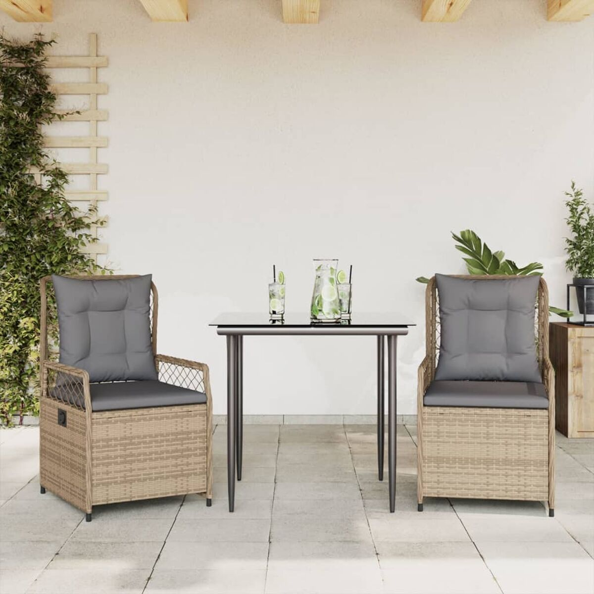 Due sedie in rattan con cuscini grigi e un tavolo con piano in vetro con bevande, su un patio con parete bianca.