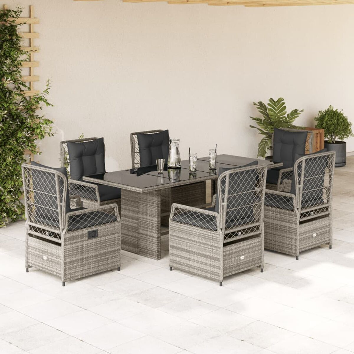 Graues Outdoor-Ess-Set aus Rattan mit schwarzen Kissen auf einer Terrasse.