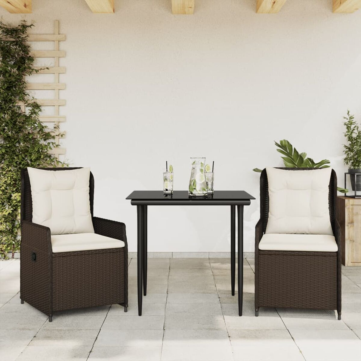 Due sedie in rattan, un tavolo con bevande e un muro bianco, con traliccio e vegetazione.