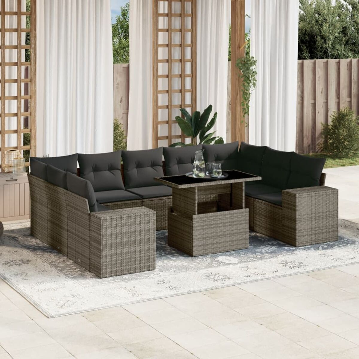 Ein Rattan-Sofaset mit Tisch und dunkelgrauen Kissen auf einem gemusterten Teppich.