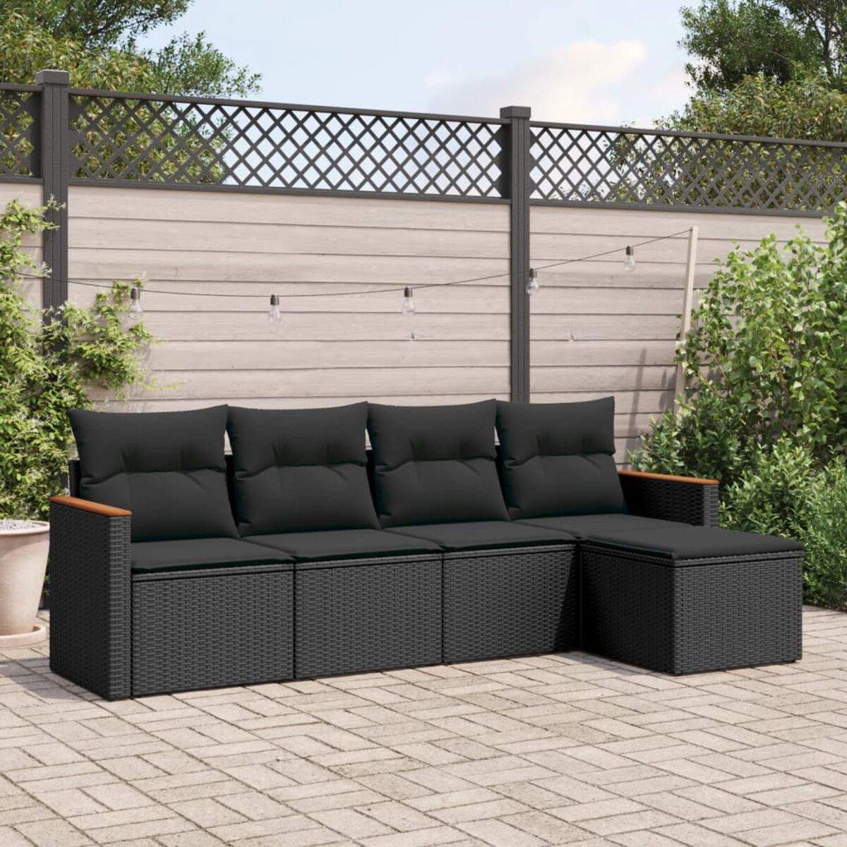 Set divani in vimini nero con cuscini neri e bracciolo in legno, su un patio.