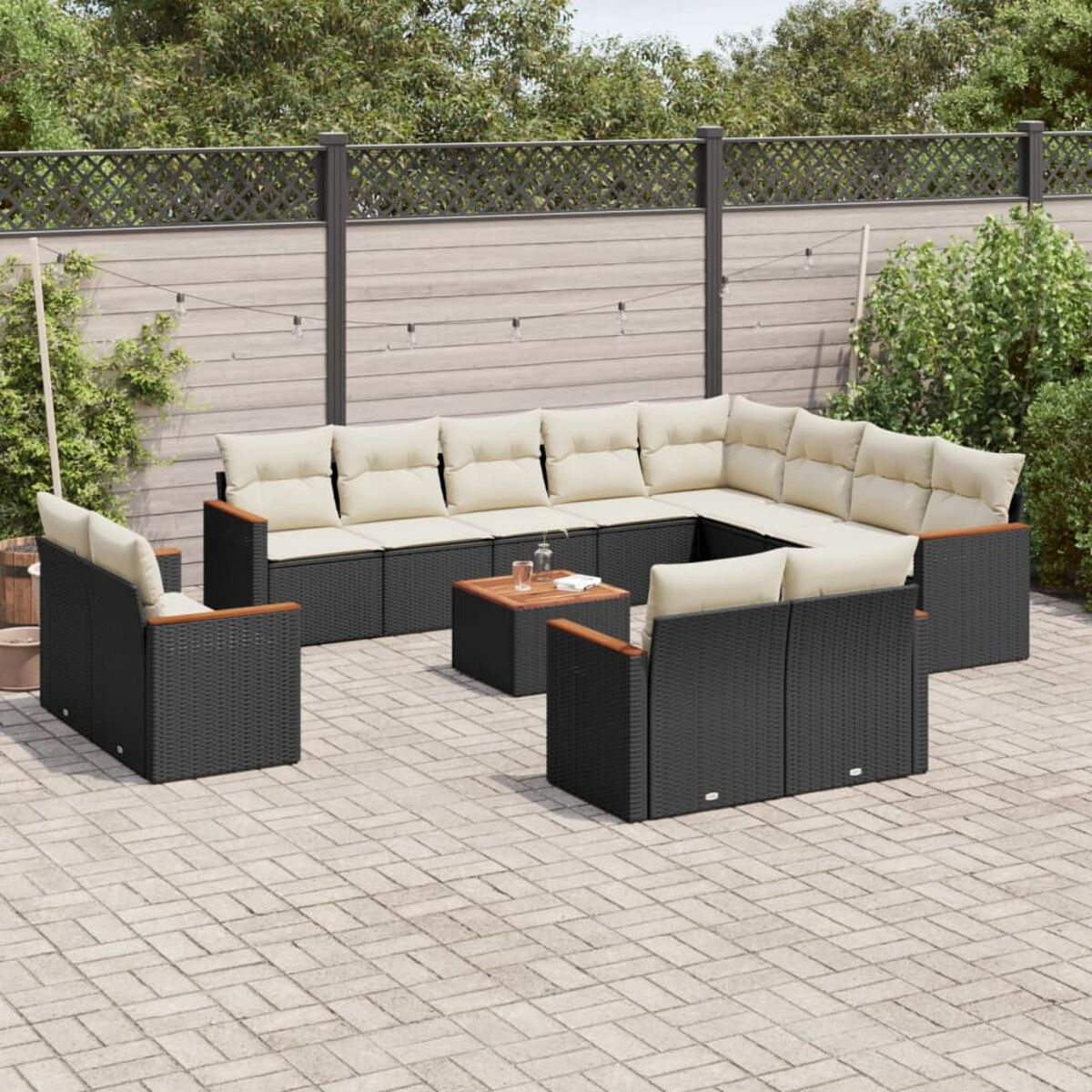 Outdoor-Ecksofa mit beigefarbenen Kissen. Steht auf einer Ziegel-Terrasse mit Holztisch und Zaun.