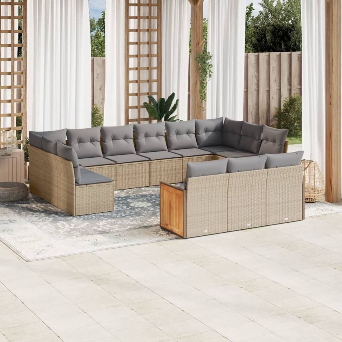 Terrassenset mit Sofa, Stühlen und Teppich. Graue Kissen. Weiße Vorhänge und Pflanzen im Hintergrund.