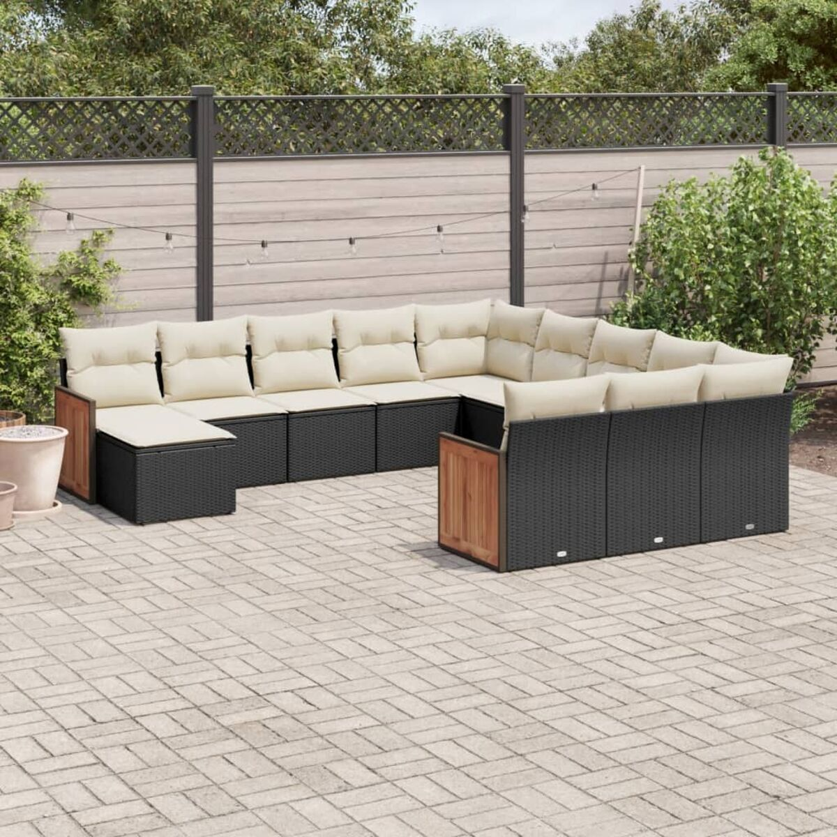 Schwarzes Korbsessel-Ecksofa mit beigen Kissen in einer Außenterrasse.