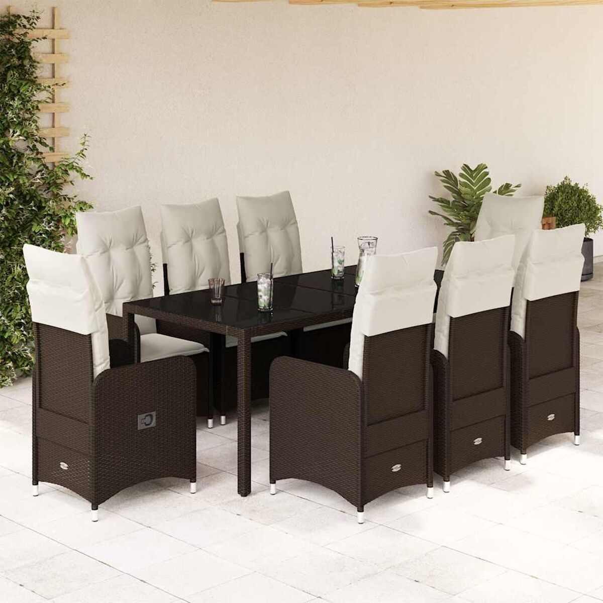 Set da pranzo in vimini marrone per esterni con tavolo in vetro nero e cuscini color crema sul patio, con piante.