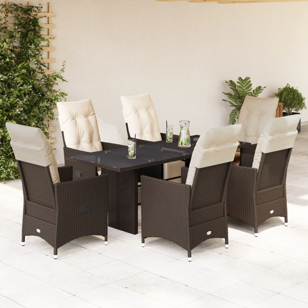 Set da pranzo in vimini marrone per esterni con tavolo in vetro nero e cuscini color crema sul patio, con piante.