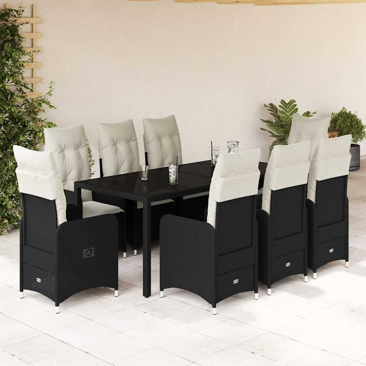 Set da pranzo da esterno con sedie in vimini nere, cuscini bianco sporco e tavolo nero, su un patio.