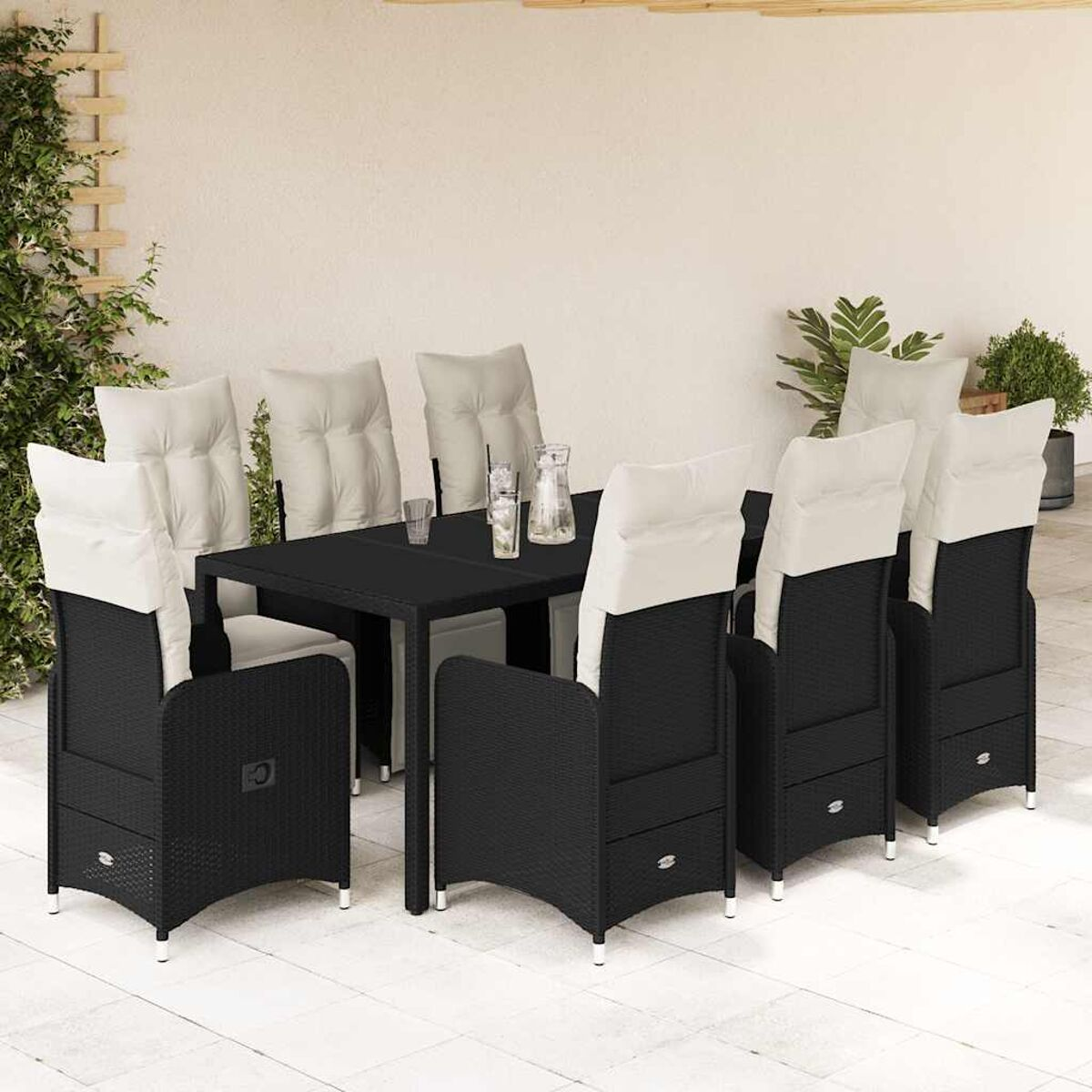Set da pranzo in vimini nero con cuscini bianchi e un tavolo nero. Su un patio.