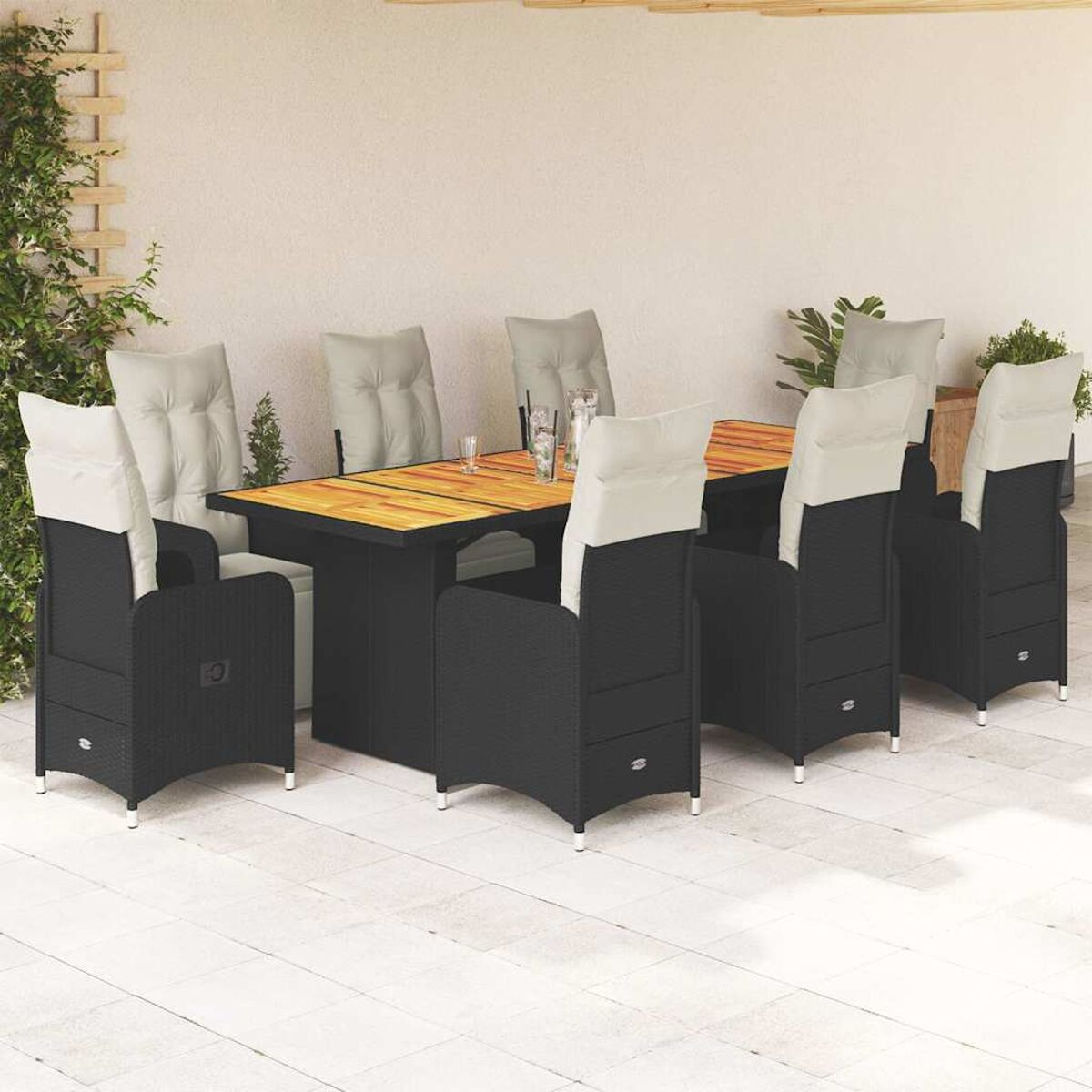 Essgruppe im Freien: schwarze Stühle, helle Kissen, Holztisch auf der Terrasse.