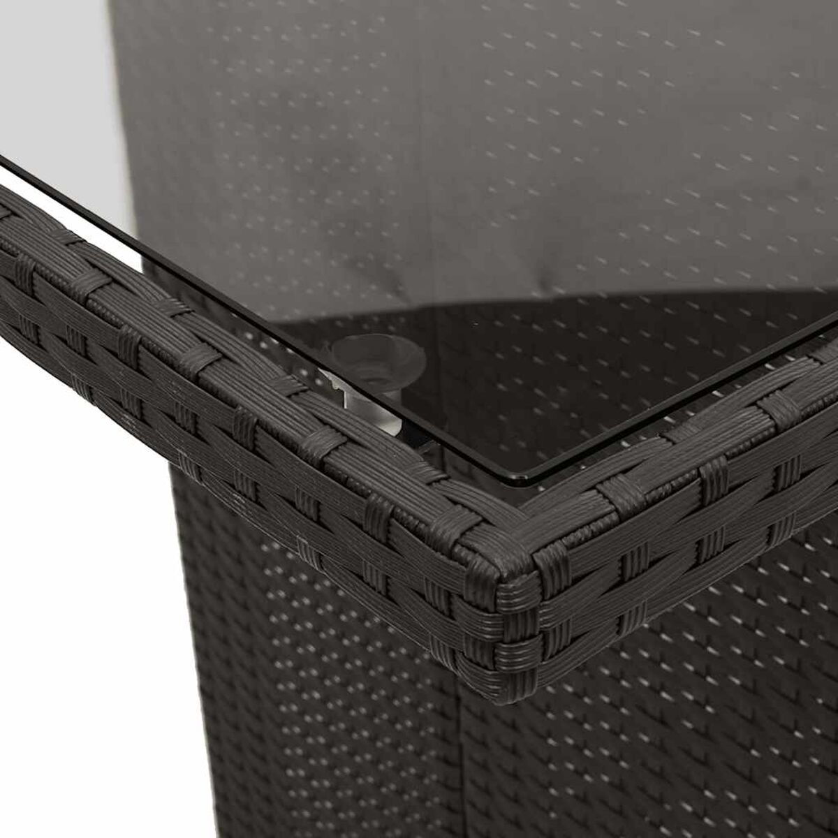 Primo piano di un tavolo in vimini nero intrecciato con piano in vetro. L'angolo del tavolo è a fuoco.