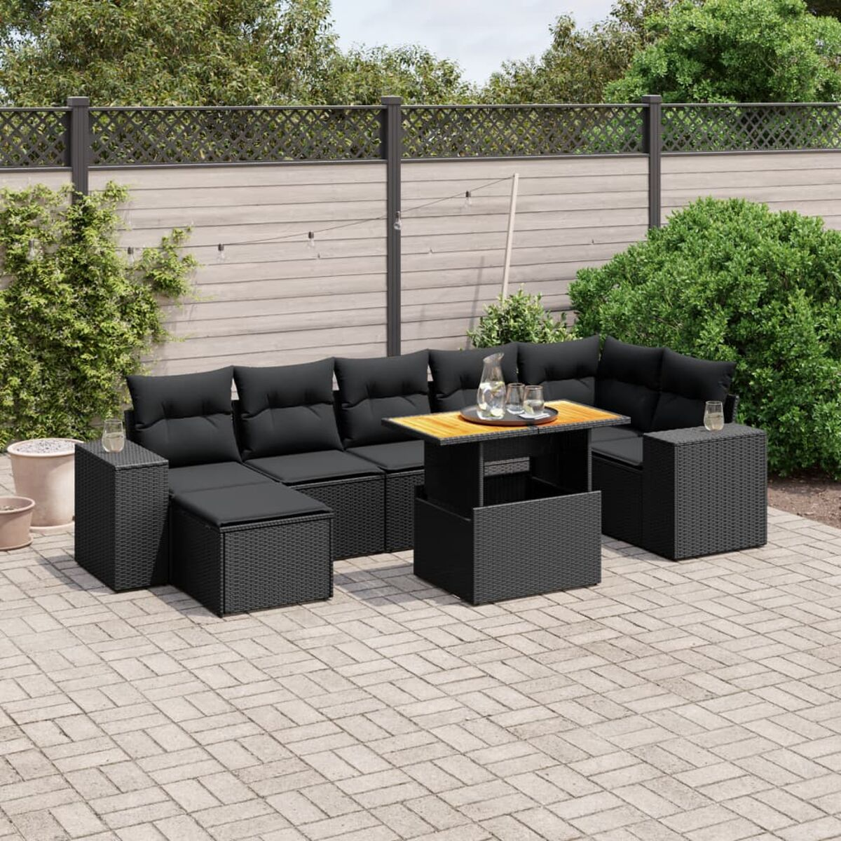 Schwarzes Sitzensemble im Freien mit Kissen, Tisch, auf einer Ziegelterrasse.