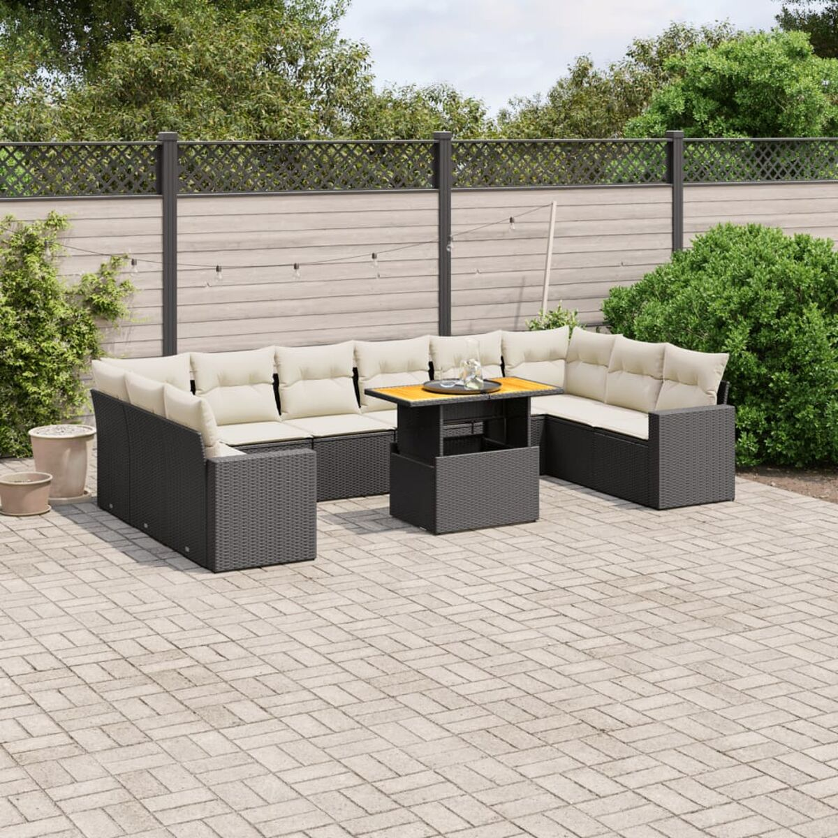 Sitzgruppe im Freien: graues Korbgeflecht, beige Kissen, Couchtisch. Ziegelterrasse.