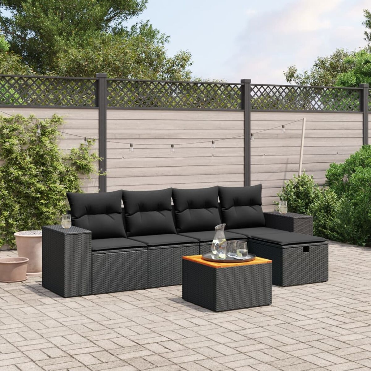 Ein schwarzes Rattan-Sofaset mit einem schwarzen Tisch, Getränken und Garten.