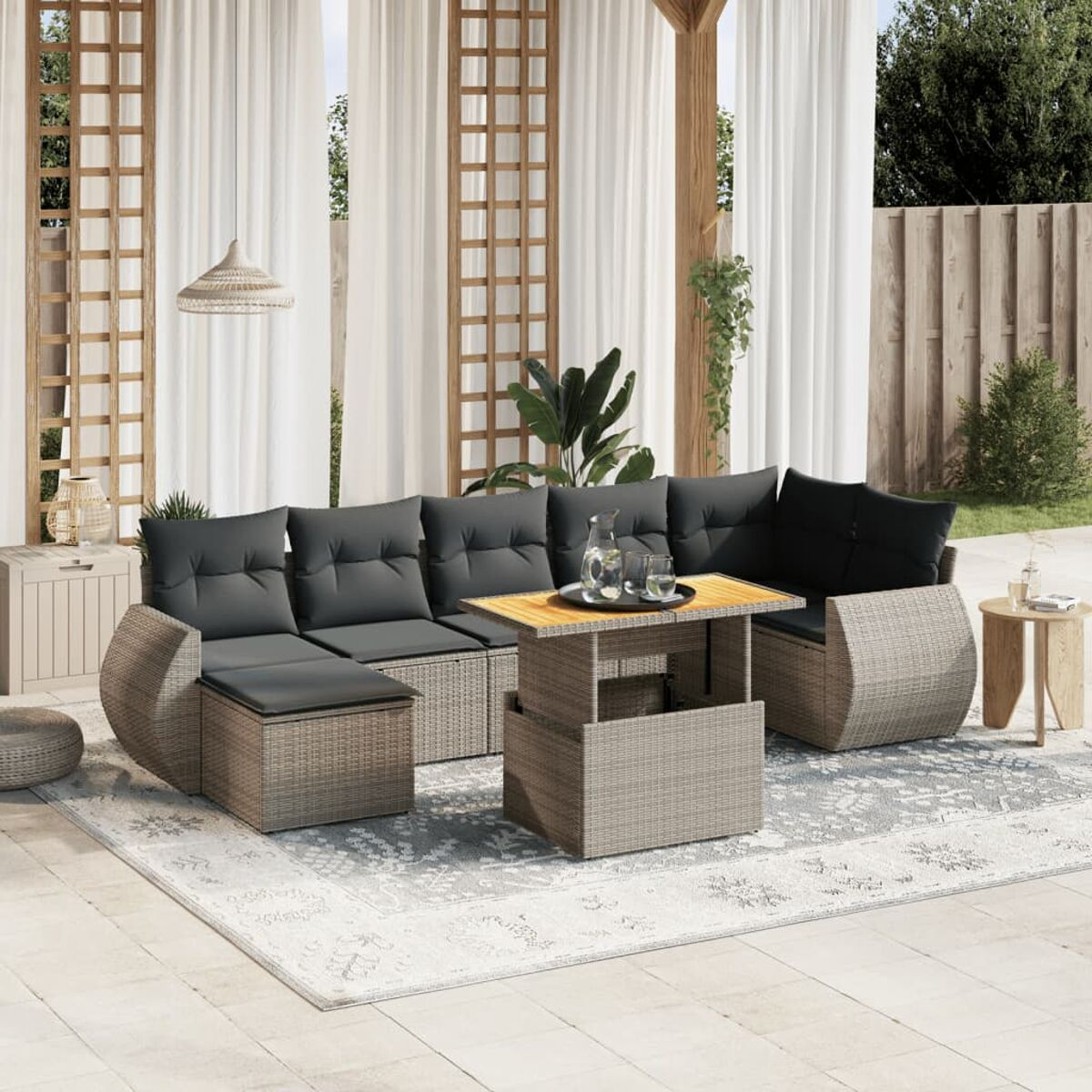 Terrasse im Freien mit Korbsofa mit schwarzen Kissen und einem Tisch mit Getränken, und einem Teppich.