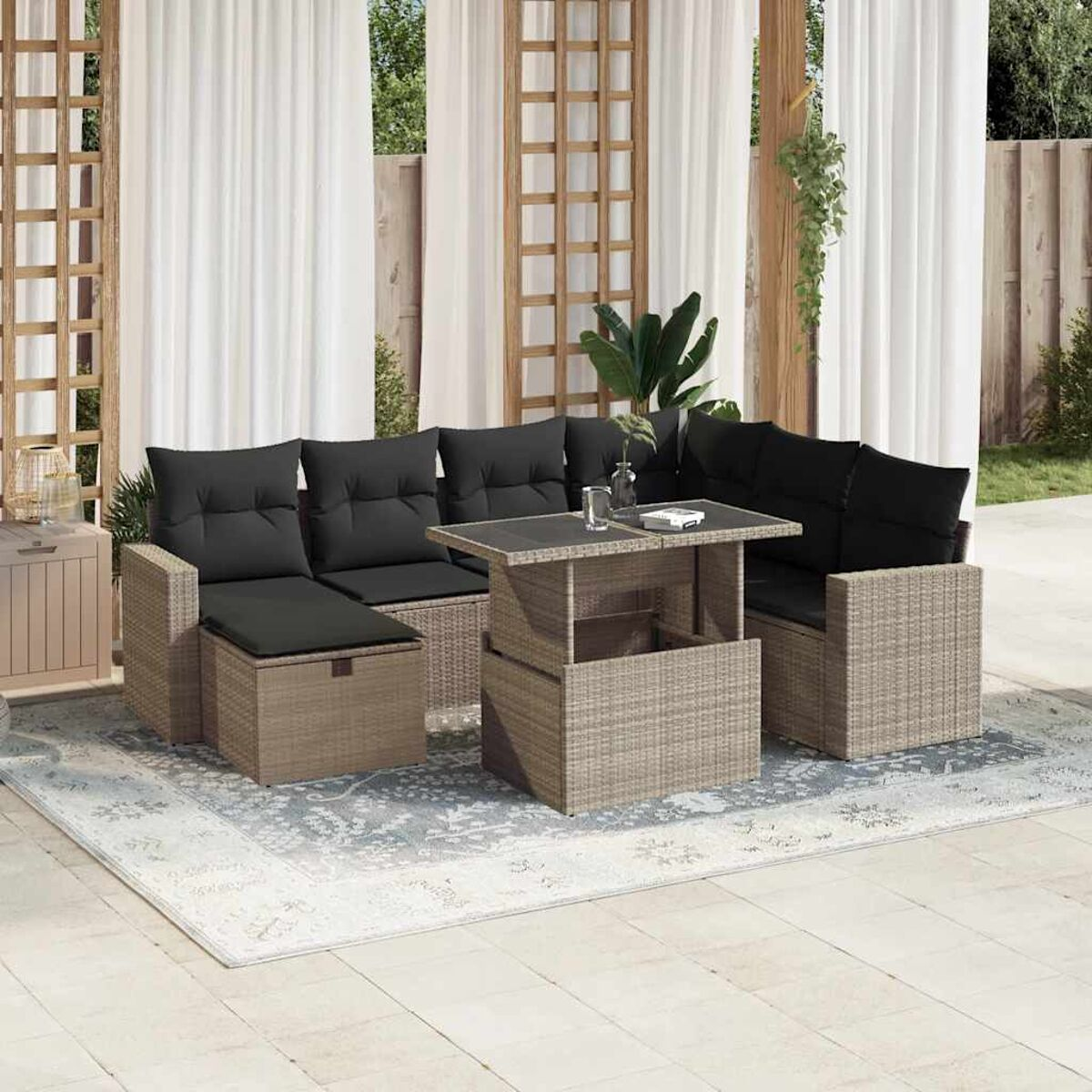 Geflochtener Ecksofa mit schwarzen Kissen und einem Tisch mit Glasplatte auf einem Teppich. Draußen.