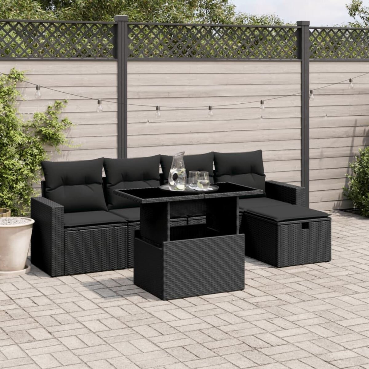 Schwarzes Outdoor-Sitzmöbel-Set aus Korbgeflecht mit Tisch und schwarzen Kissen. Terrasse im Freien.