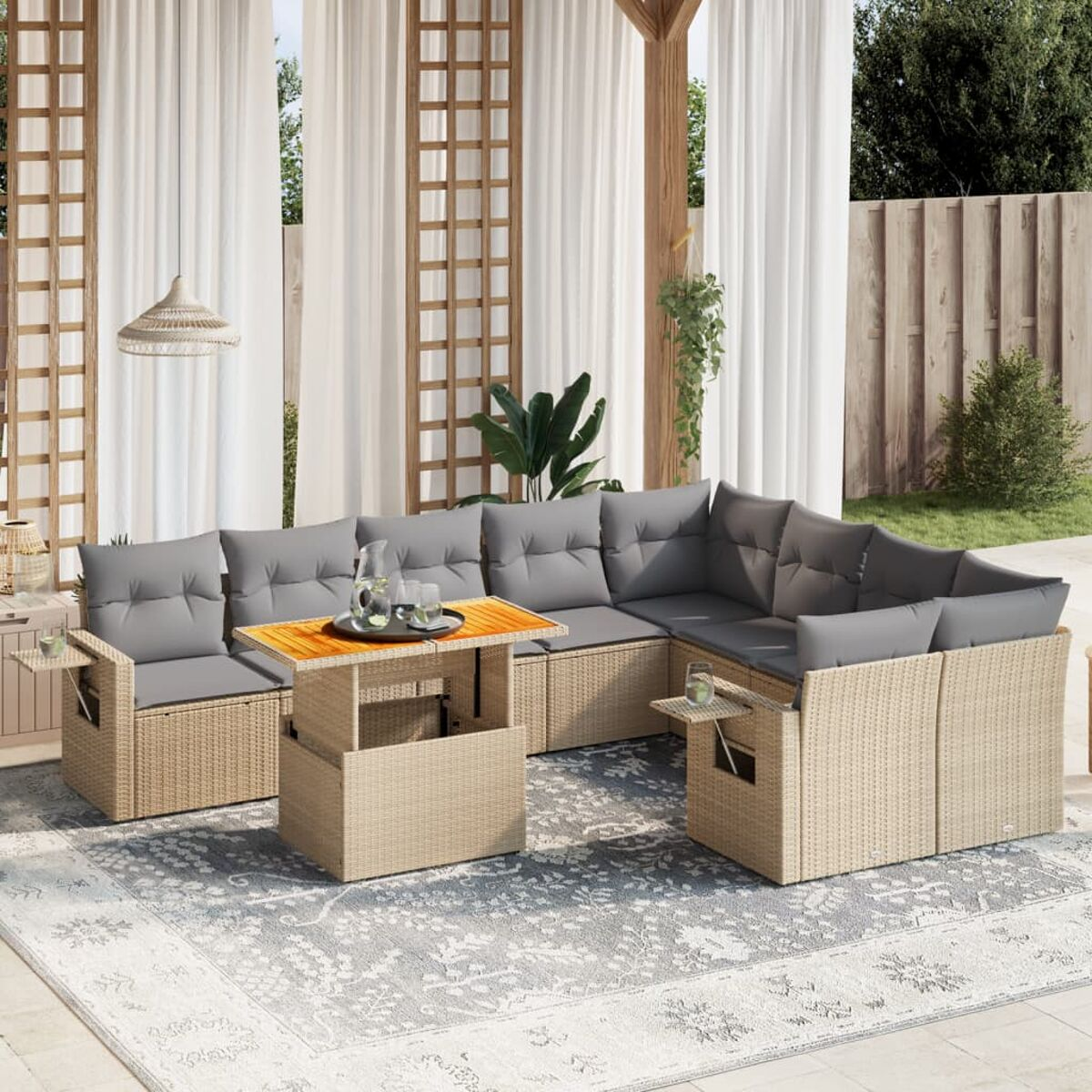Geflochtenes Terrassenset mit grauen Kissen. Enthält einen Tisch und ein Ecksofa. Hintergrund: weiße Vorhänge.