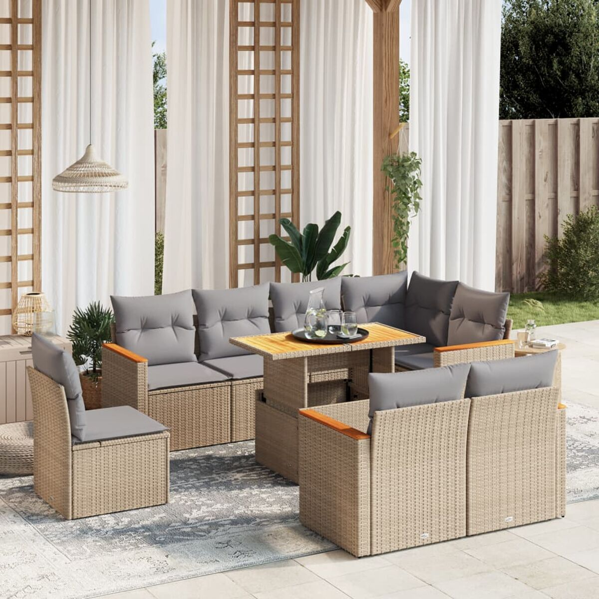 Rattan-Sofa-Set für den Außenbereich mit grauen Kissen auf einer Terrasse mit Vorhängen und einem Teppich.